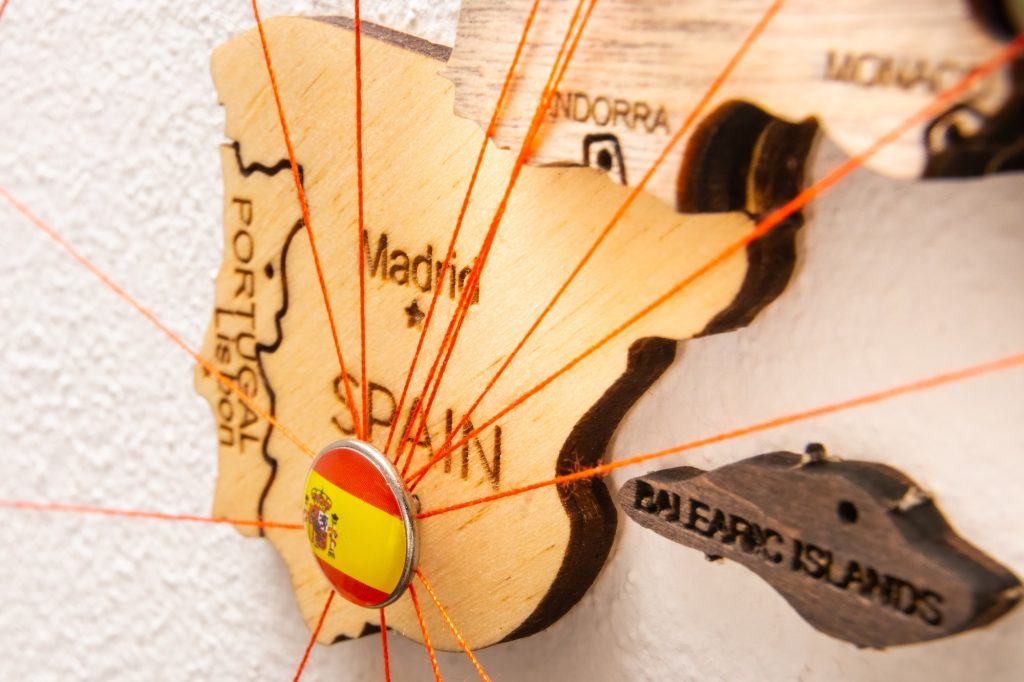 Spain flag on the pin with red thread showed the paths on the wooden map.