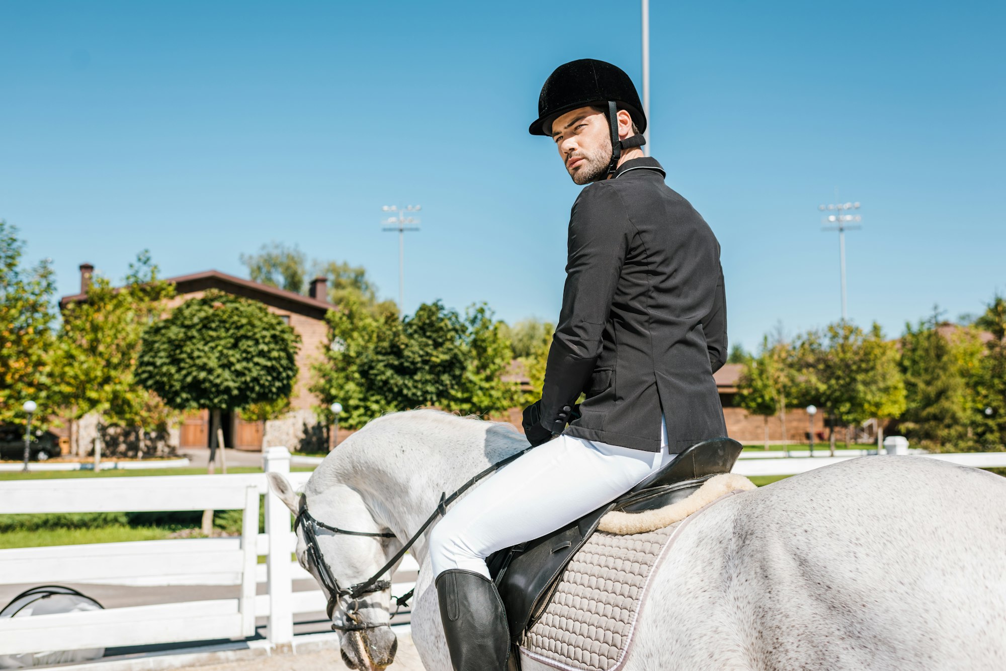 handsome male equestrian in professional apparel sitting on horseback at horse club
