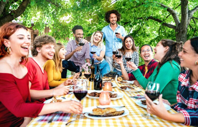 Happy people having fun toasting wine out side farm house